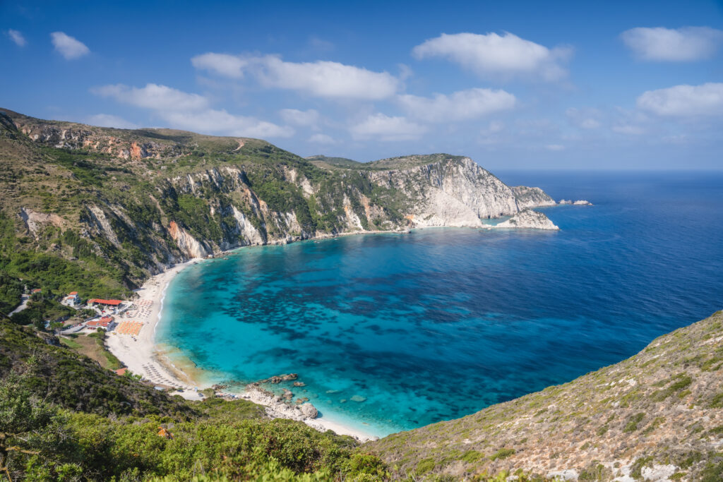View from on top of cliff looking down at the clear blue water of Petani Beach in Kefalonia, Ionian Islands, Greece.