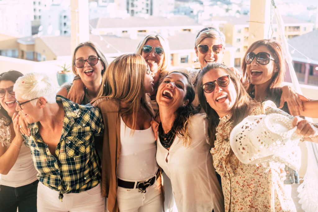 A group of women in sunglasses laughing during a women's travel experience