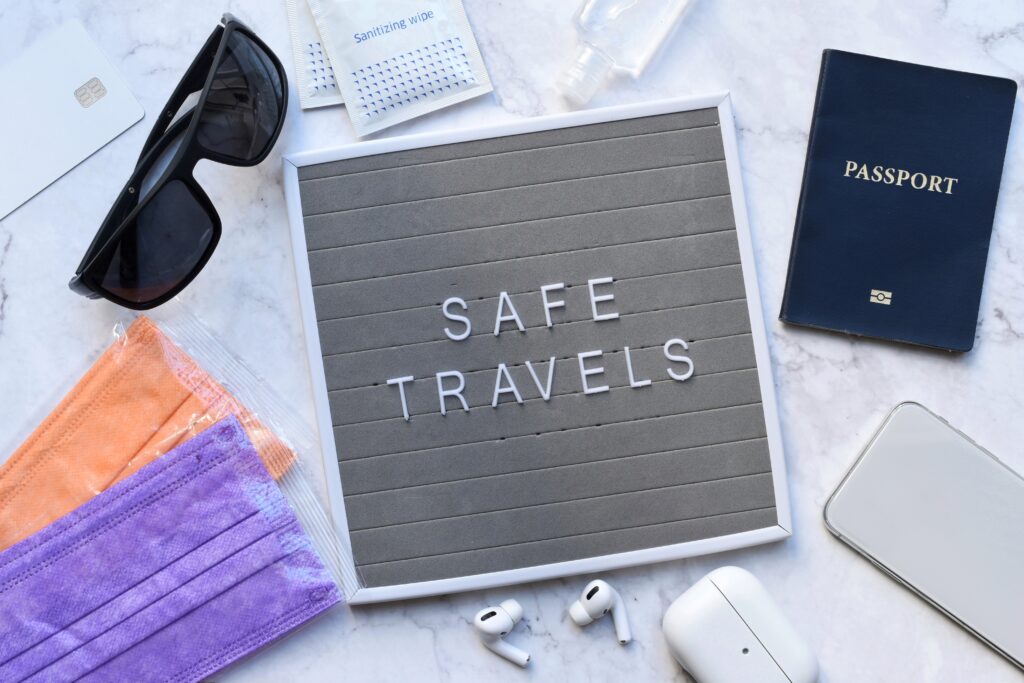 A sign that reads "Safe Travels" sits on a table surrounded by other travel items.