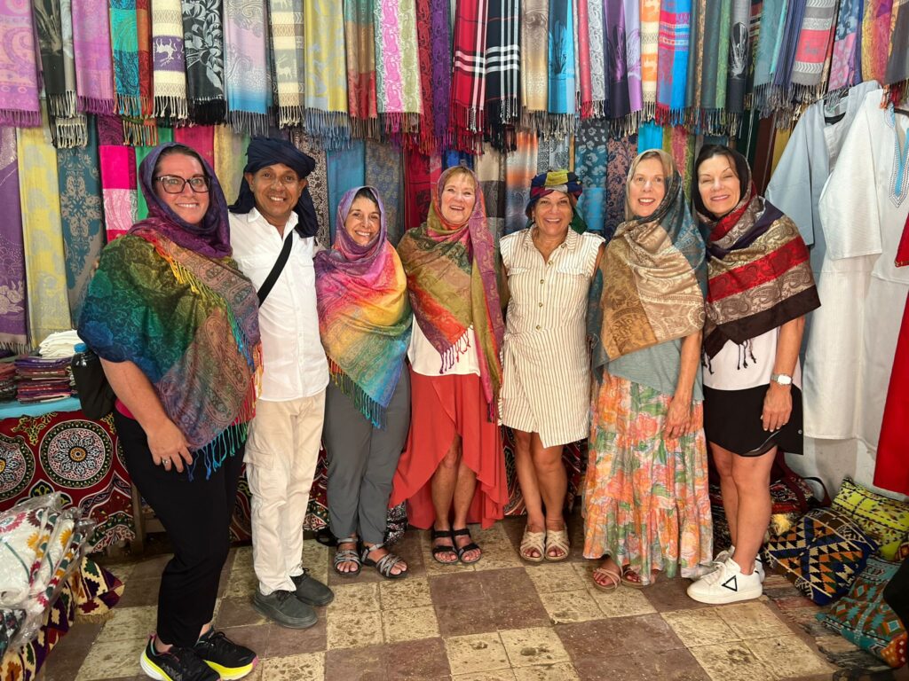 A group of women on vacation in Egypt pose in traditional clothing with local artists.