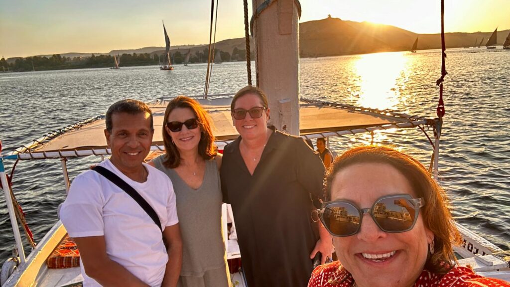 A group of woman on a trip to Egypt pose smiling with a captain on his boat on the Nile River in Egypt.